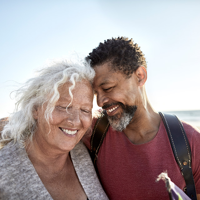 Smiling older man rests his forehead on the head of a smiling older woman