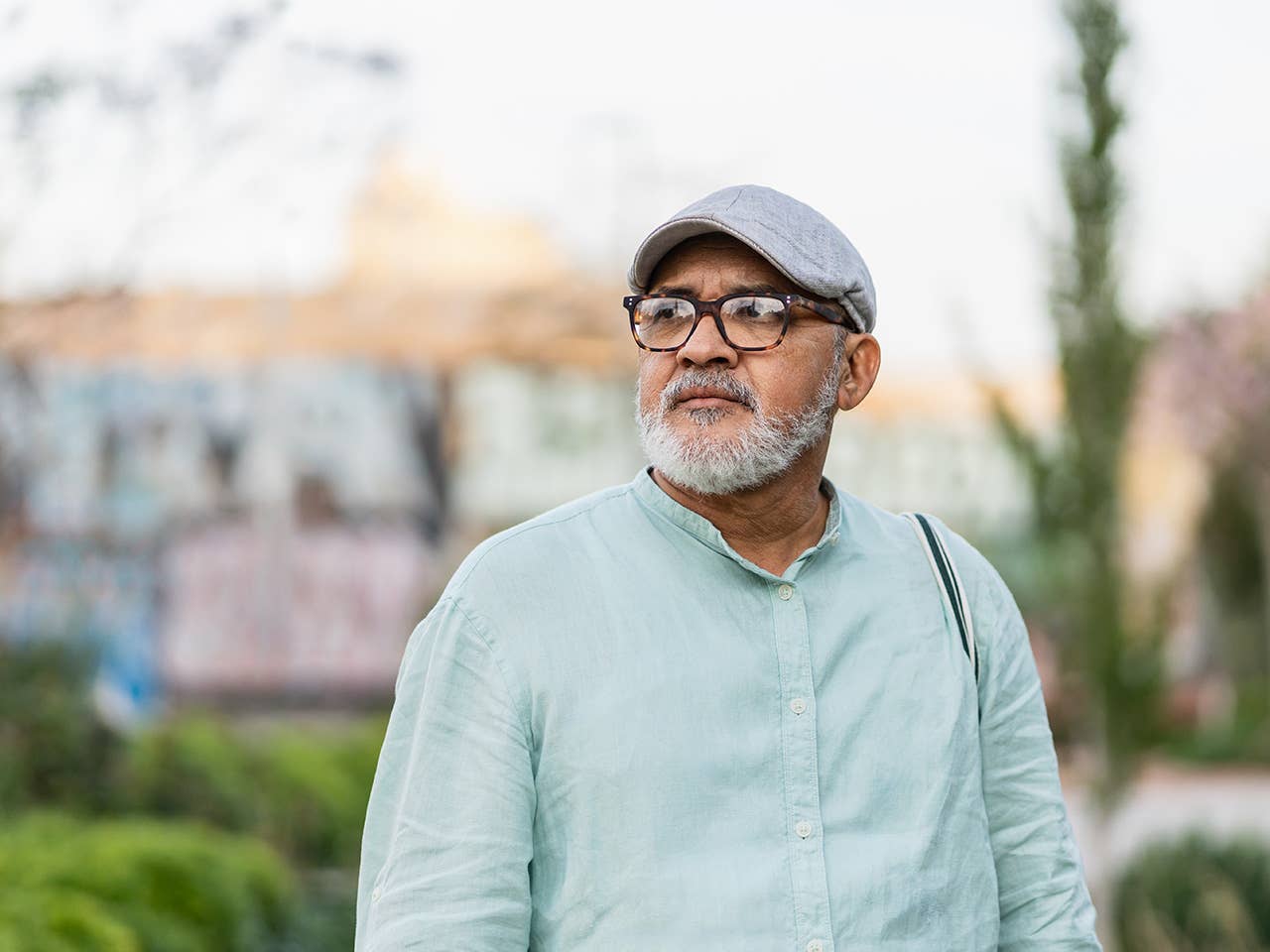 Older white man with glasses and a grey goatee stands outdoors in the evening sun