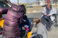 A diverse group of individuals loading a van with bags of food, showcasing community support and engagement in local initiatives.