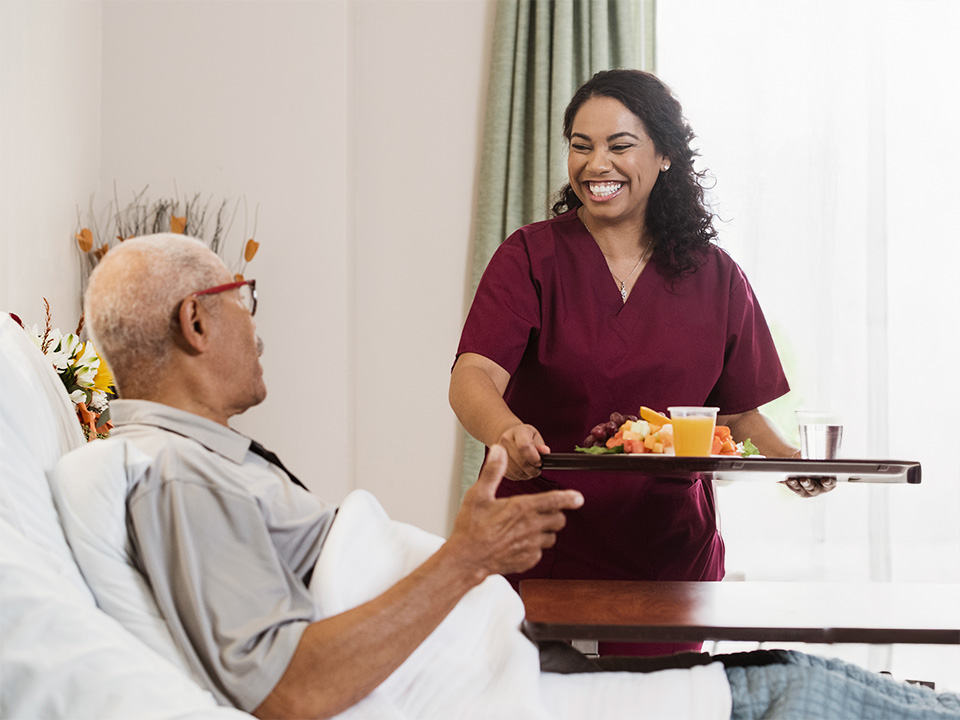 hospital staff delivering meal to a patient in their hospital room