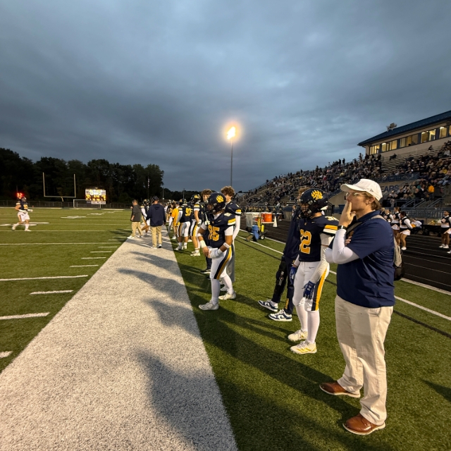 View of team and staff members from the sideline of a football game