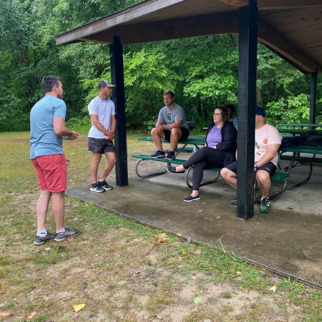 residents sitting under a pavilion at a park listening to someone talking
