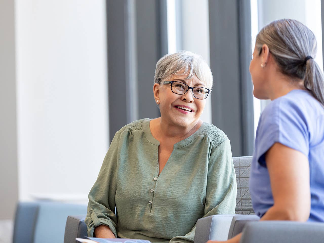 Smiling elderly woman speaks with a Corewell Health heart and vascular specialist in an exam room