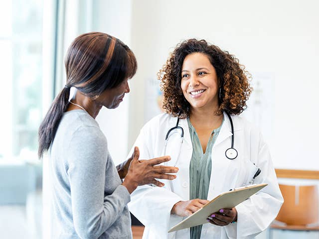 A woman engaged in conversation with a doctor inside a medical office.