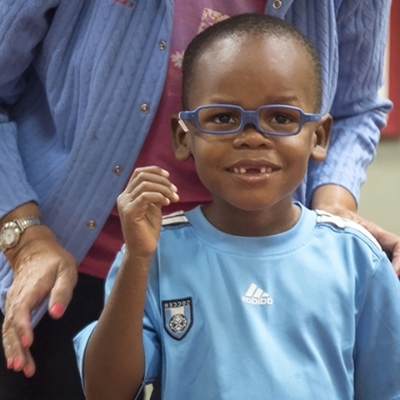 Young Black boy in a light blue shirt wearing blue glasses