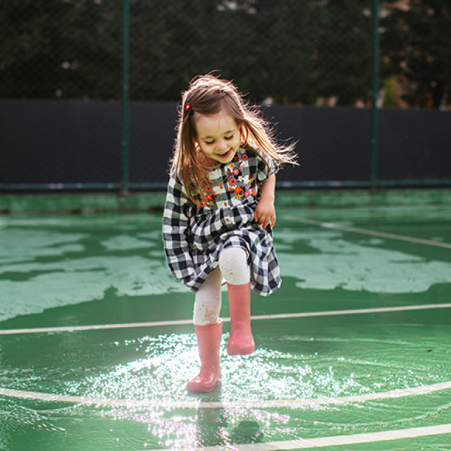 Smiling Caucasian girl splashes in a puddle of water