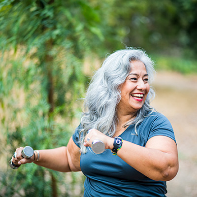 female outside walking and carrying weights while exercising