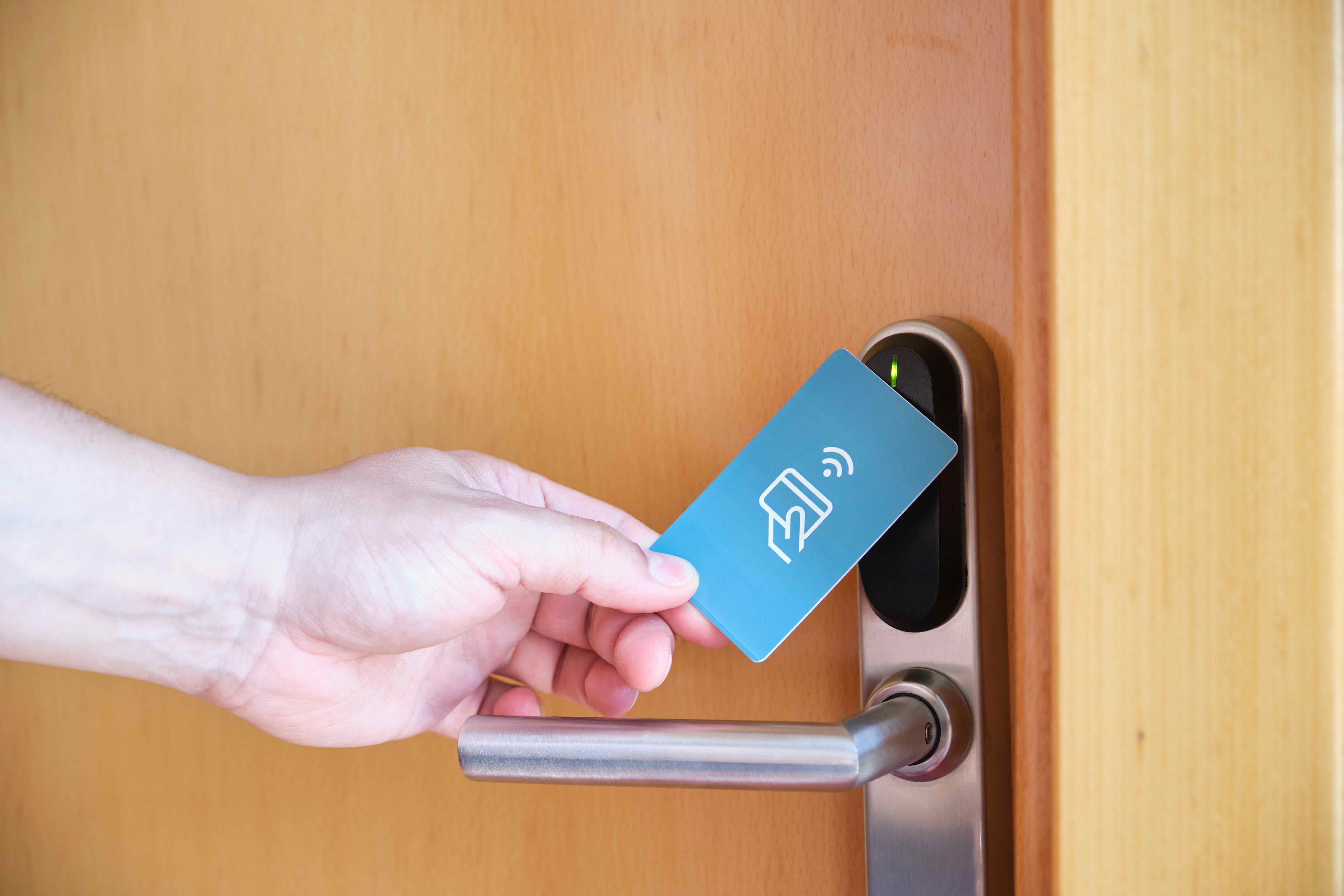 hand holding a swipe card in front of a door