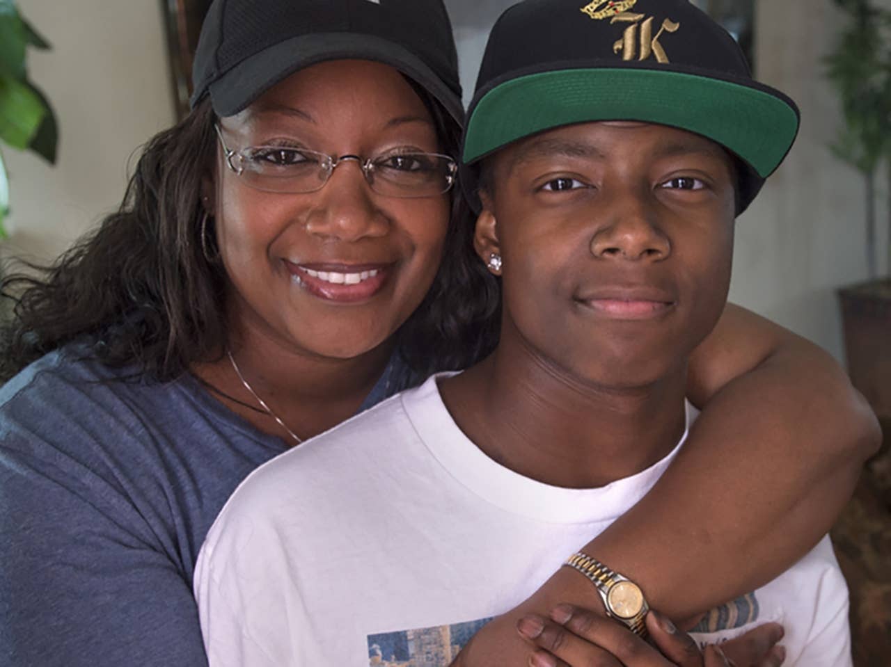 Smiling Black woman hugs her son from behind