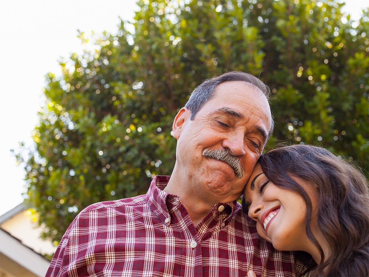Older man with grey hair hugs his adult daughter