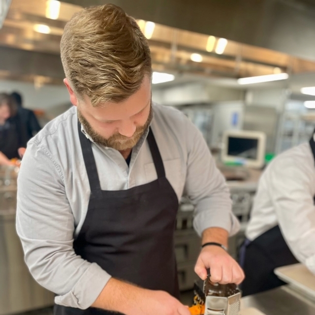 culinary chef cutting a carrot on a cutting board