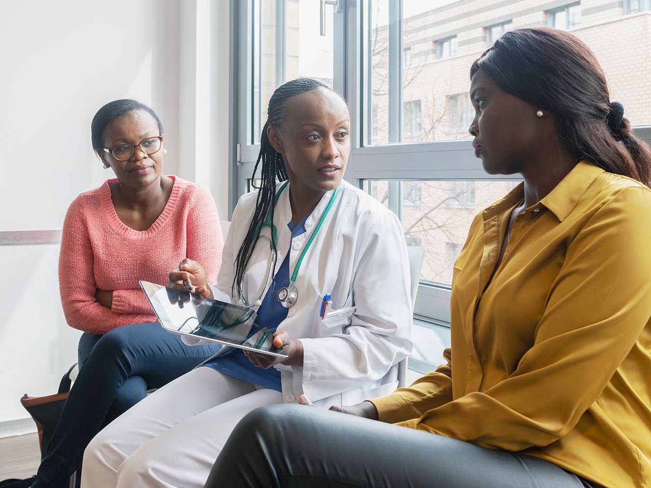 Three women converse with a doctor, focusing on medical concerns and personal health discussions.
