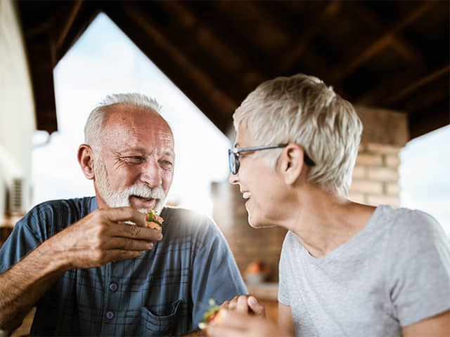 Older adults sharing a healthy meal together at home, enjoying fresh food and social connection while aging well.