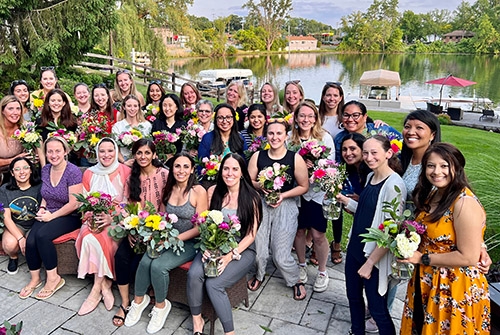 A group of women in Emergency Medicine posing together with flowers, celebrating their unity and role as role models.