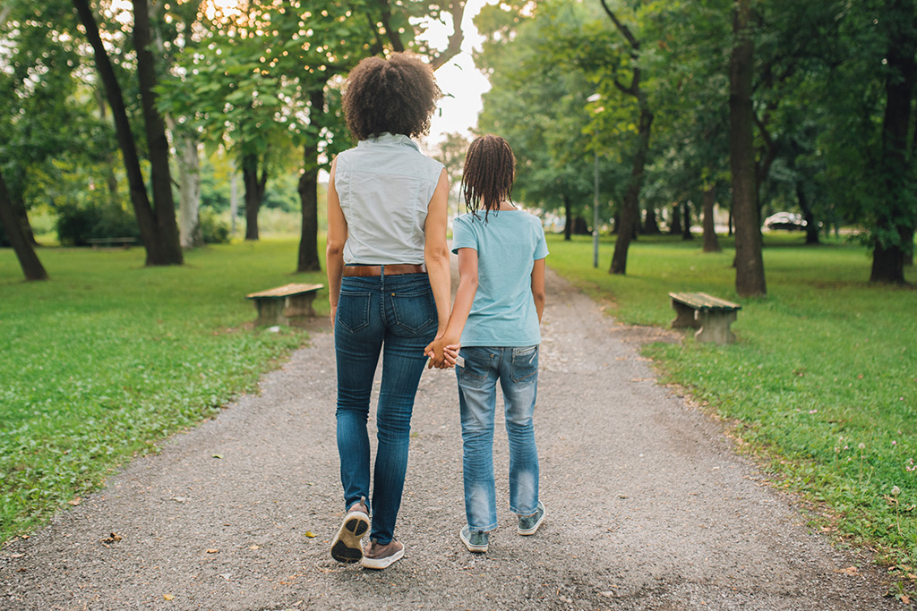 dark haired women walking through a park with dark haired daughter