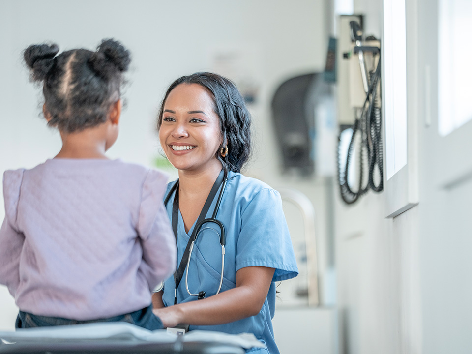 A woman converses with a young girl in a hospital setting, providing comfort and support during a medical visit.
