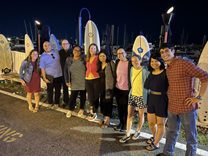 A diverse group of individuals stands together in front of surfboards, ready for a day of surfing and camaraderie.