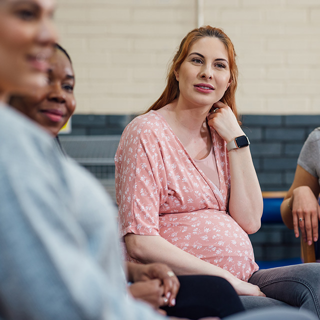 A group of women seated in a circle, engaged in conversation and sharing ideas.