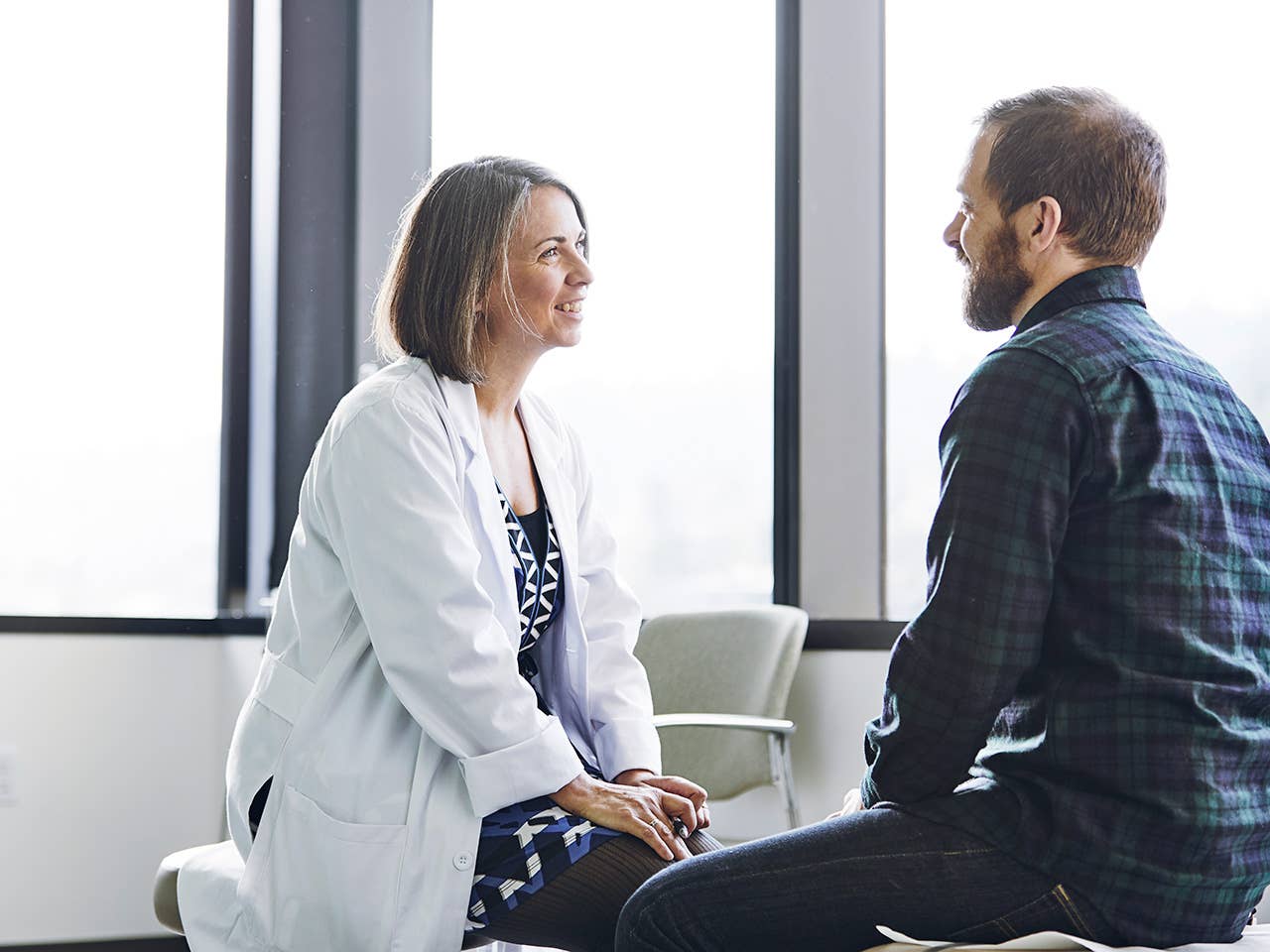 Female doctor in white lab coat sits across from male patient