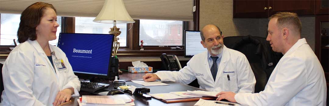 A trio of doctors in white coats collaborating at a desk, focused on their work and sharing insights.