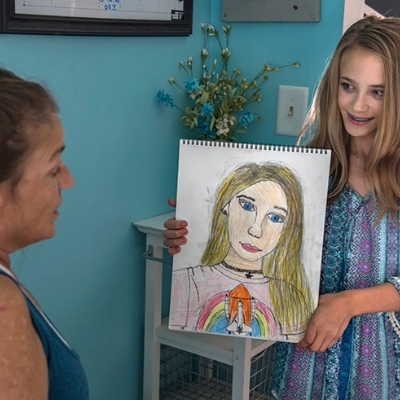 Preteen girl shows off a self portrait drawing