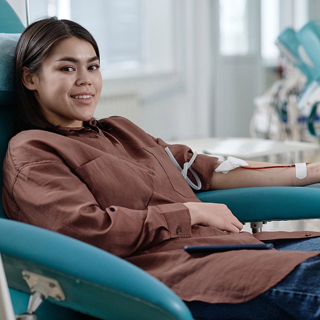 A woman seated in a chair donating blood.