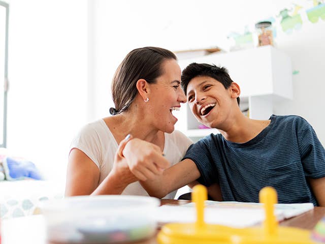Preteen boy and his mother smiling and interacting at the table.