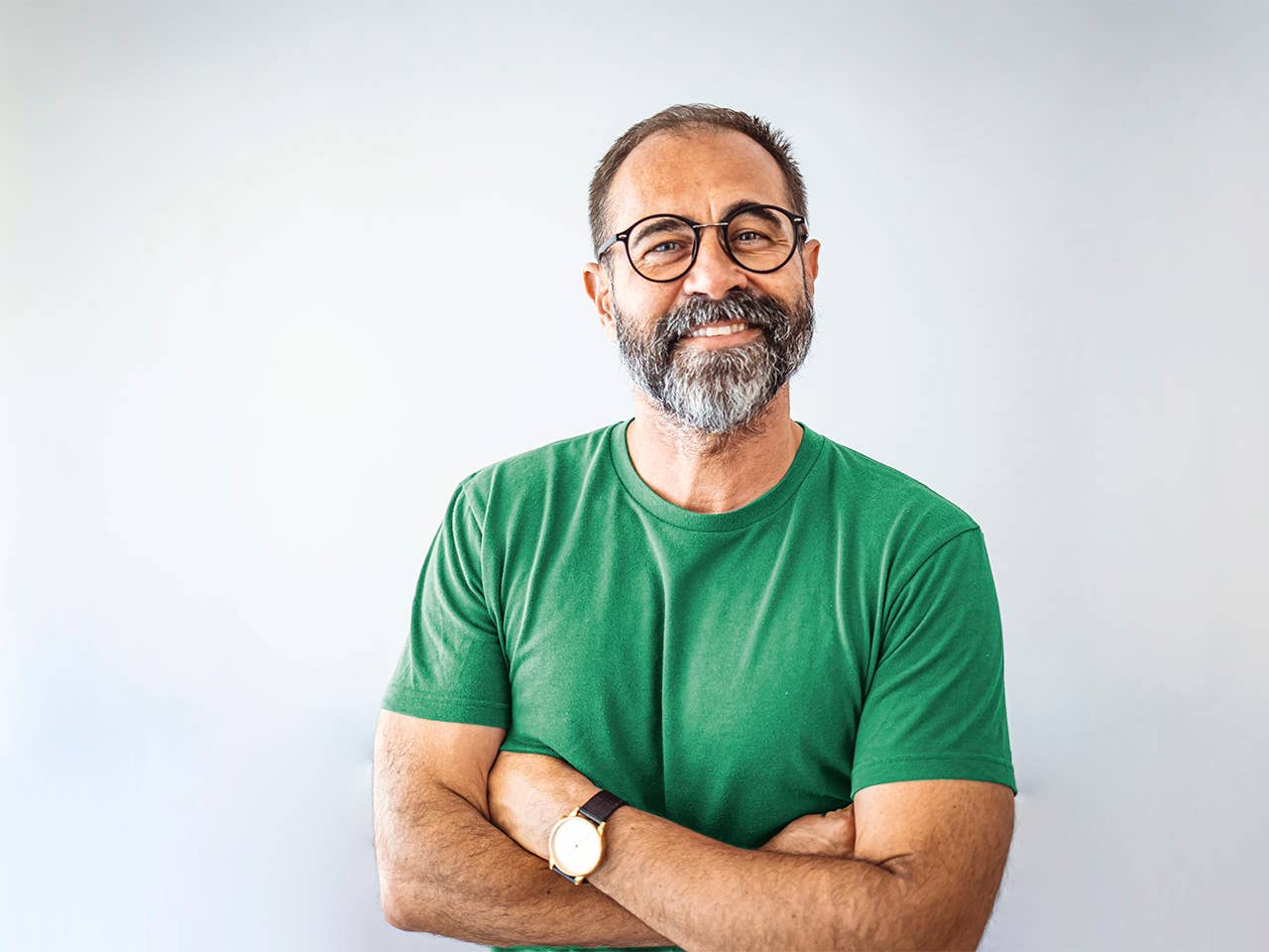 Smiling white man with a grey beard and glasses crosses his arms