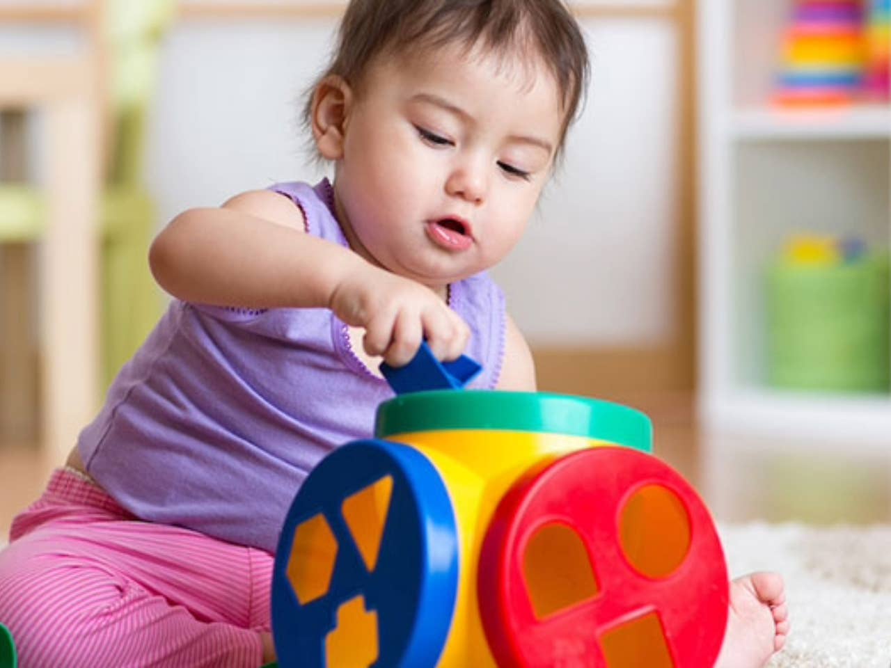 Little girl developing skills by playing with blocks and toys.
