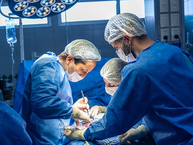 Group of people in scrubs performing an operation on a patient in the operating room