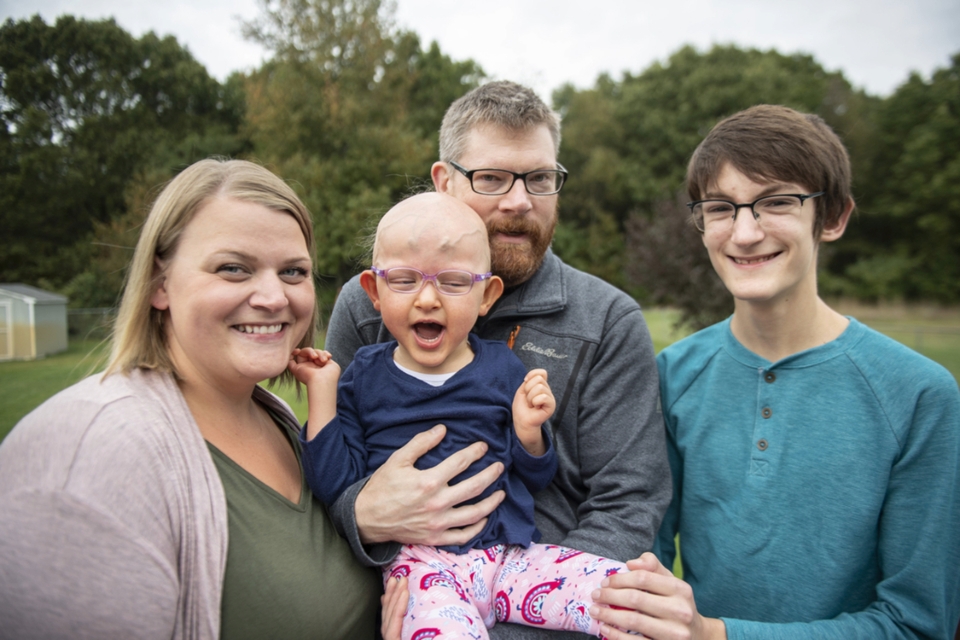 Mother and father stand with teenage son and young daughter outdoors