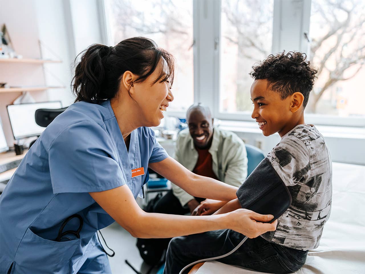 A nurse assists a young boy in measuring his blood pressure in a clinical setting.