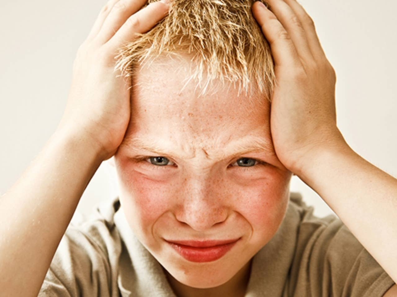Boy holding his head because he has a headache.