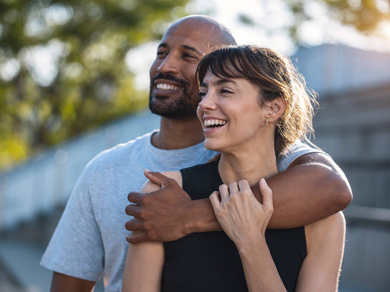 A man and woman smile warmly while embracing each other in a joyful moment.