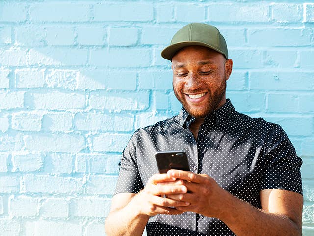 Smiling Black man uses his phone to fill out the Corewell Health primary care quiz