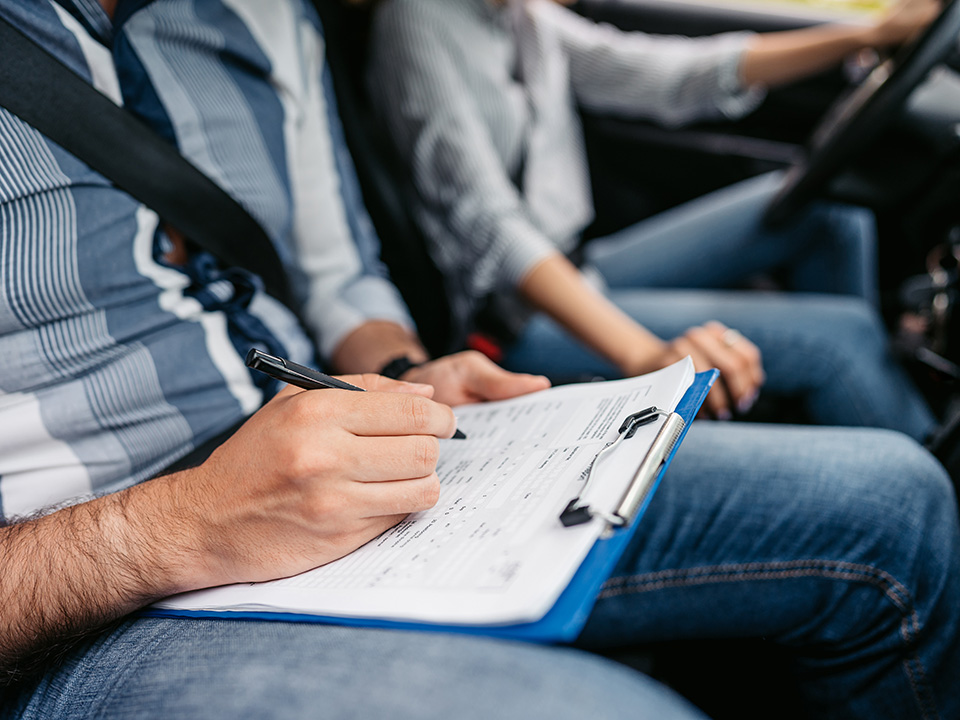 Closeup of driving instructor in passenger seat with a clipboard