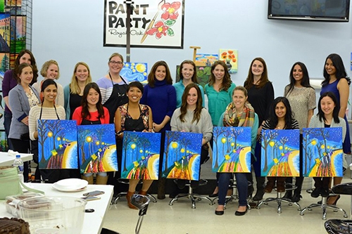 A group of women proudly displaying their paintings during a resident outing, showcasing their artistic talents and creativity.
