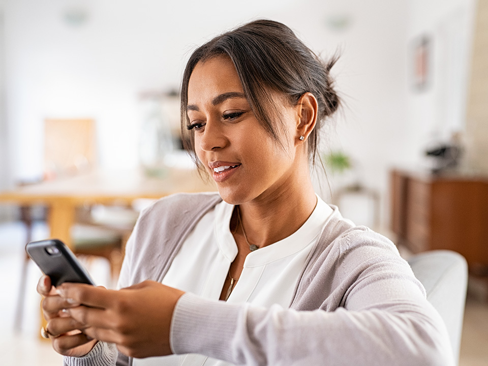 Person using a smartphone while seated at home during a virtual healthcare appointment or video visit.