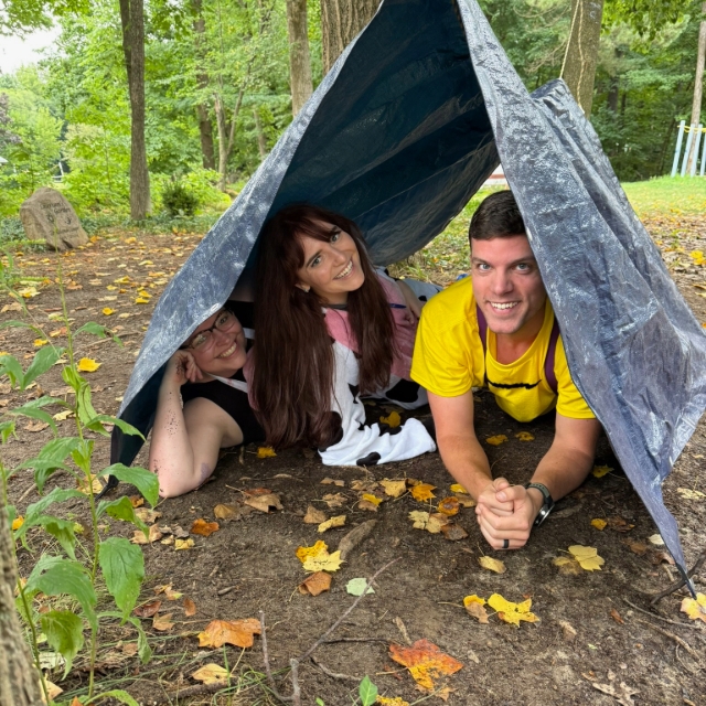 Three residents in a tent smiling for a picture during a wilderness retreat