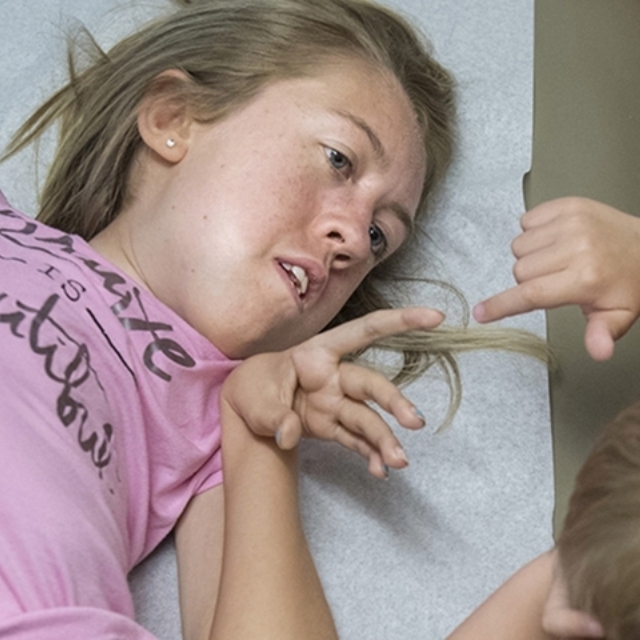 Teenage girl in pink shirt reaches out and touches fingers with her brother