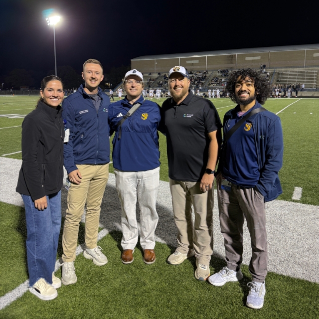 Medical staff members posing for a group picture on the sideline of a football game