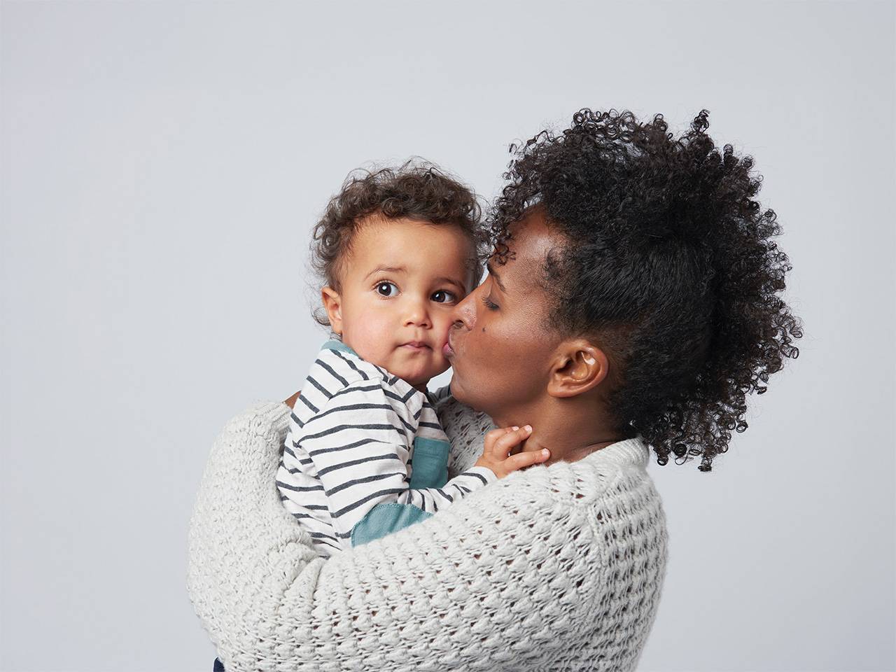 Person holding and kissing an infant, highlighting nurturing care and protection for babies and young children.