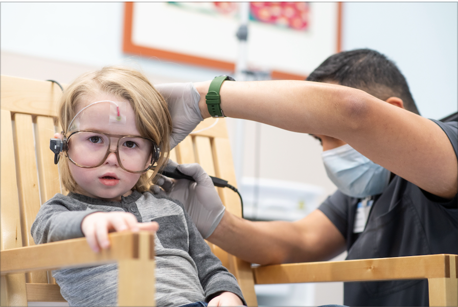 nurse with a sensor on the back of a small girl's head