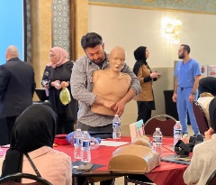 Dr. Najeeb Bangash helps a woman with a dummy as he volunteers to teach essential life support skills to local youth.