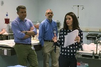 A group of faculty members discussing around a table in a hospital setting, representing Graduate Medical Education in Southeast Michigan.
