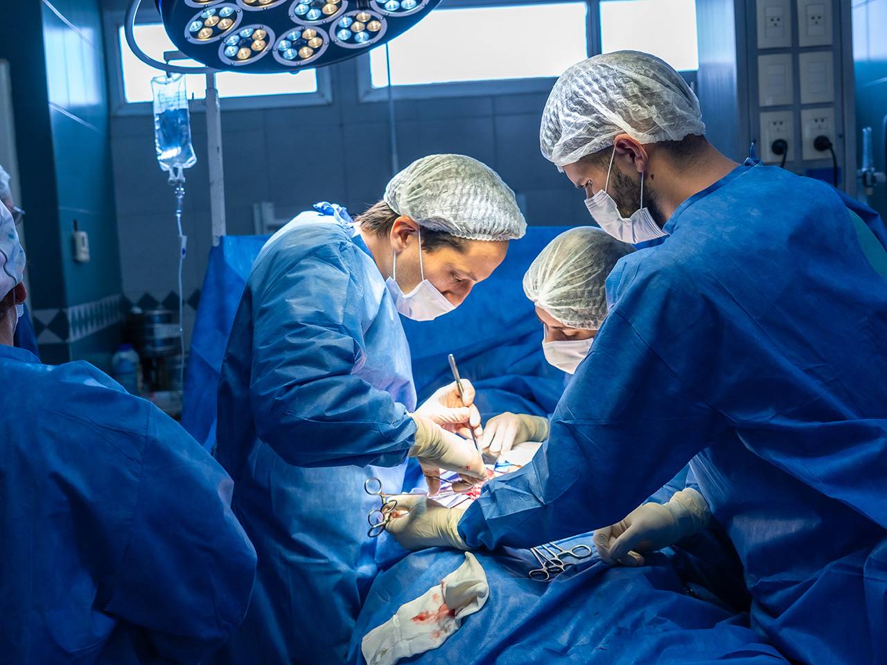 Group of people in scrubs performing an operation on a patient in the operating room