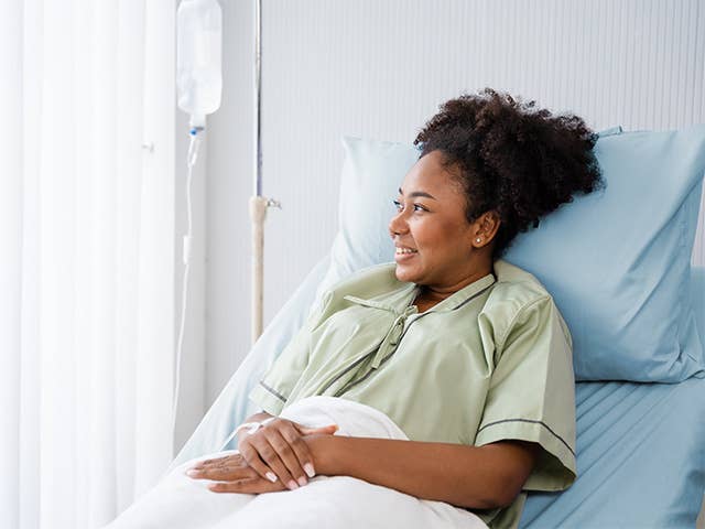 Black woman with curly hair rests in a hospital bed