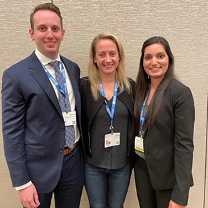 Three individuals stand together in front of a wall, symbolizing collaboration and support in a mentoring environment.