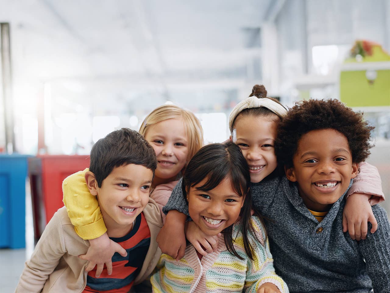 A group of children hugging and smiling at school.