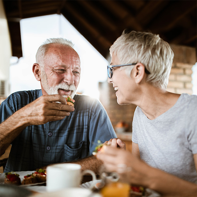 Older adults sharing a healthy meal together at home, enjoying fresh food and social connection while aging well.